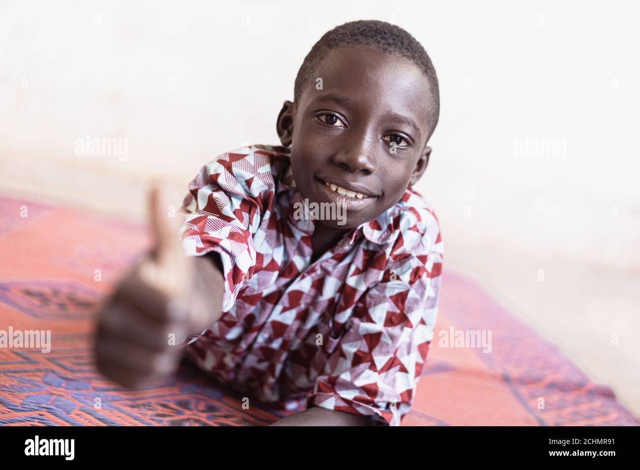 Scolaro africano che dà i pollici di fronte a White Sfondo Foto Stock