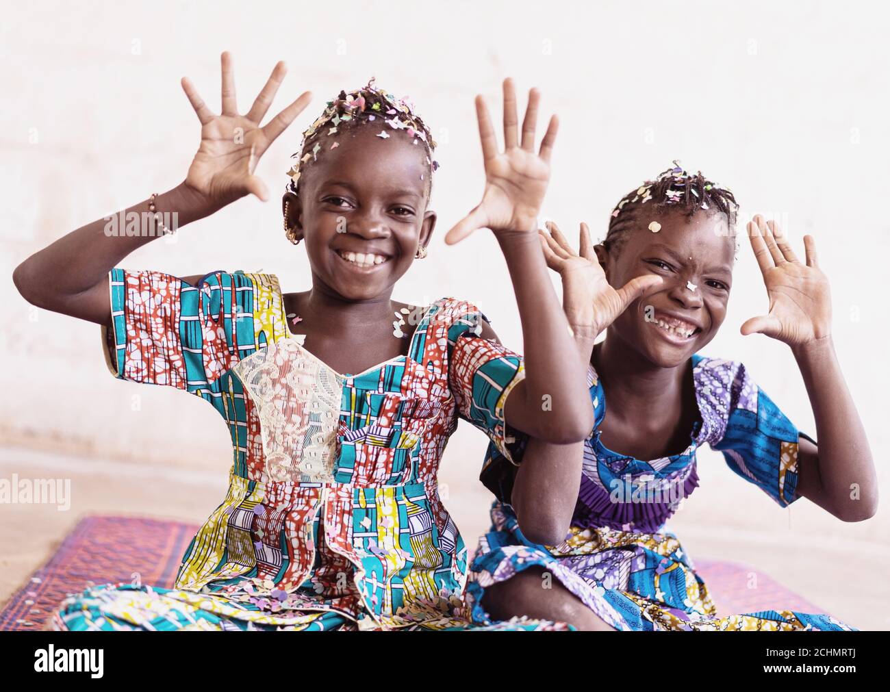 Real African Girls Enjoying Hands Up Throwing Confetti from their hands in a White Room Foto Stock