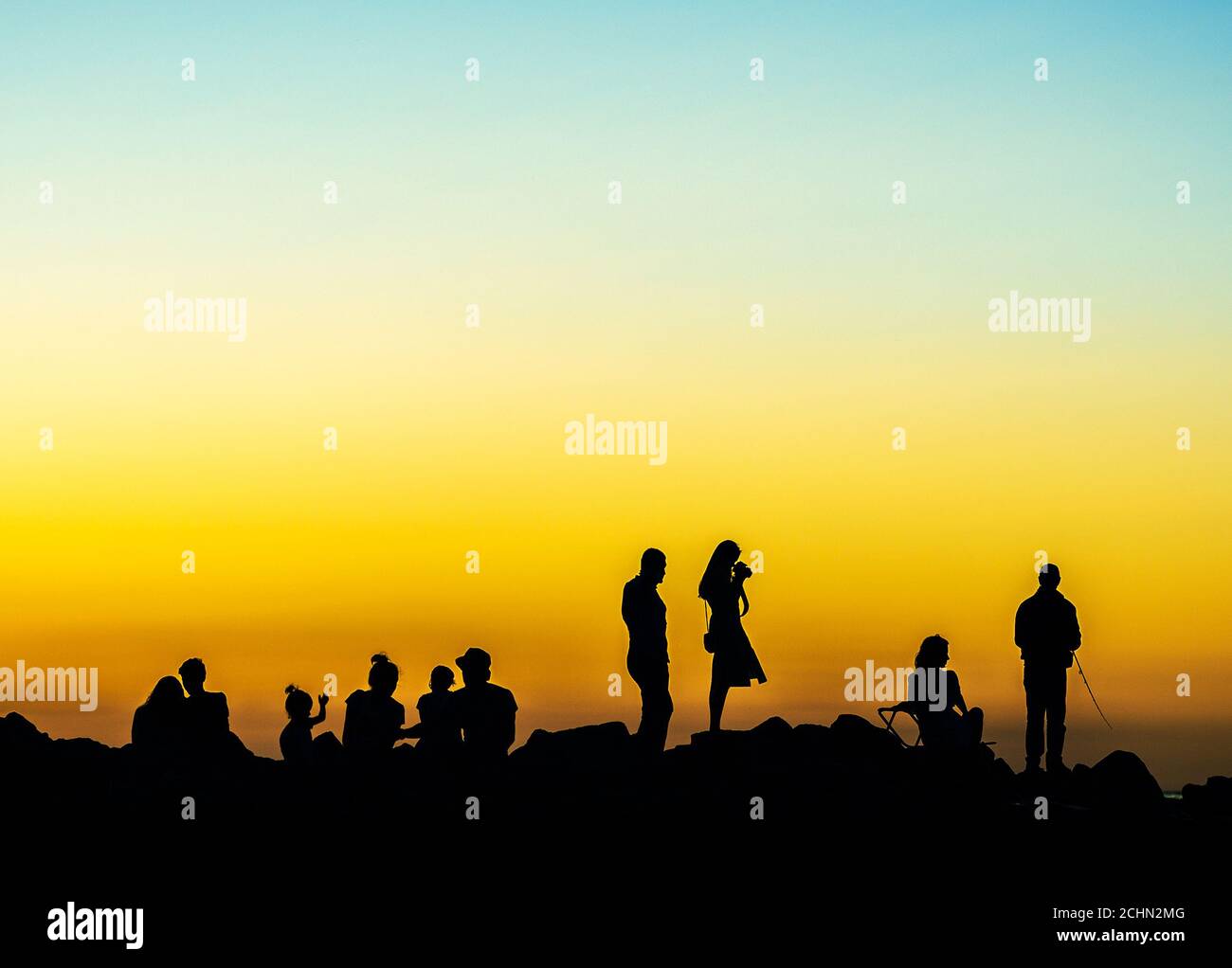varie persone al tramonto sulla costa rocciosa Foto Stock