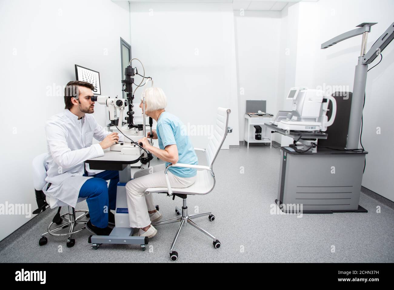 Optometristo e paziente anziano durante la diagnosi della vista in una clinica moderna. Esame visivo e controllo visivo Foto Stock