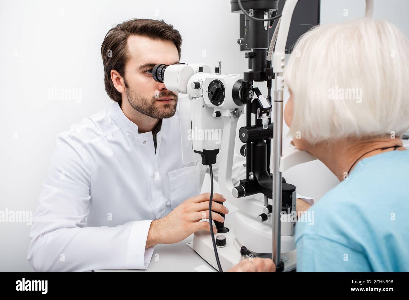 Controllo ottico della visione di un paziente anziano utilizzando una lampada a fessura. Esame oculare paziente con cataratta Foto Stock