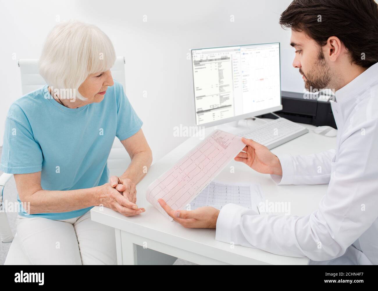 il cardiologo consulta una donna anziana sui risultati di un cardiogramma e di test. Aritmia e malattie cardiache, diagnosi Foto Stock