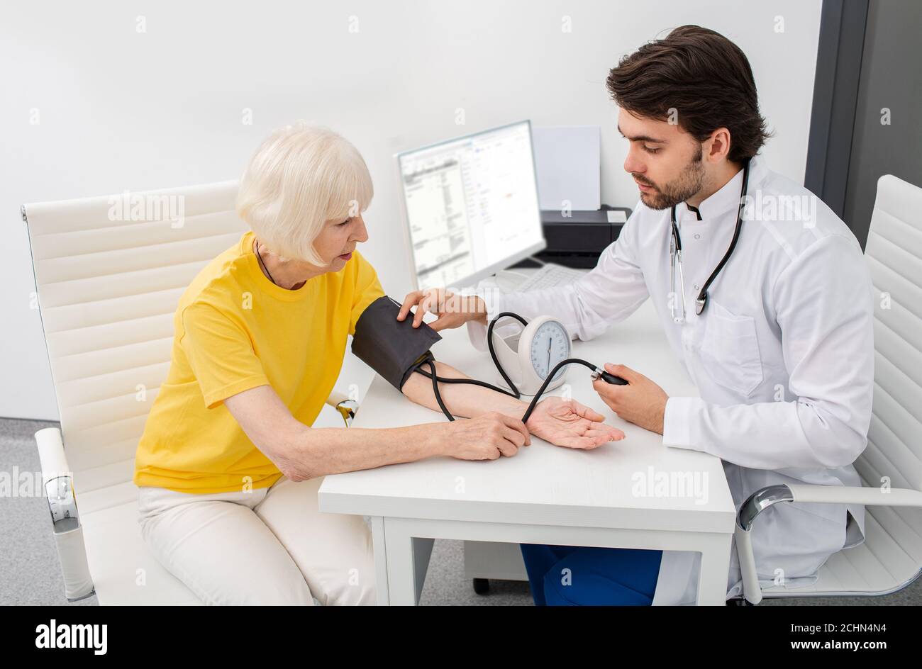medico terapeuta in clinica moderna misura la pressione corporea di una donna anziana. Prevenzione di malattie di ipertensione, aterosclerosi e insufficienza cardiaca Foto Stock