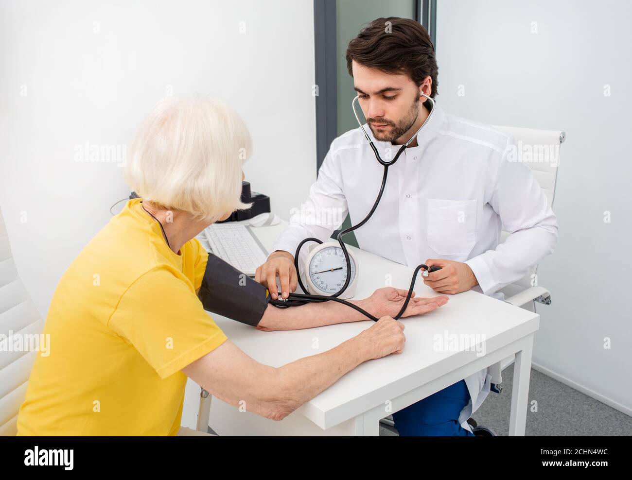 medico terapeuta in clinica moderna misura la pressione corporea di una donna anziana. Prevenzione di malattie di ipertensione, aterosclerosi e insufficienza cardiaca Foto Stock