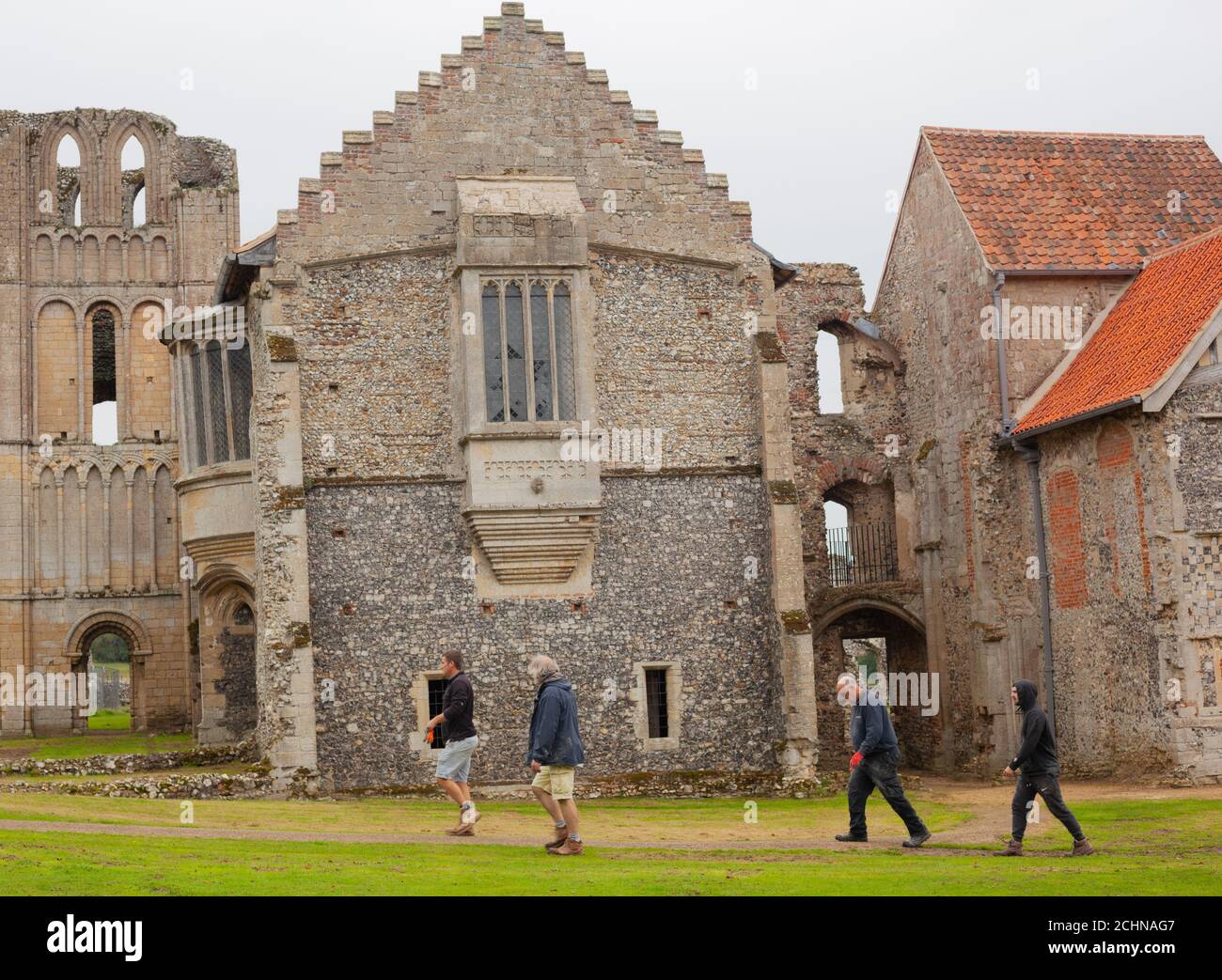 Quattro conservatori che camminano vicino alle rovine del Priorato di Castello Acre, un priorato storico cluniaco nel villaggio di Castello Acre, Norfolk, Gran Bretagna Foto Stock