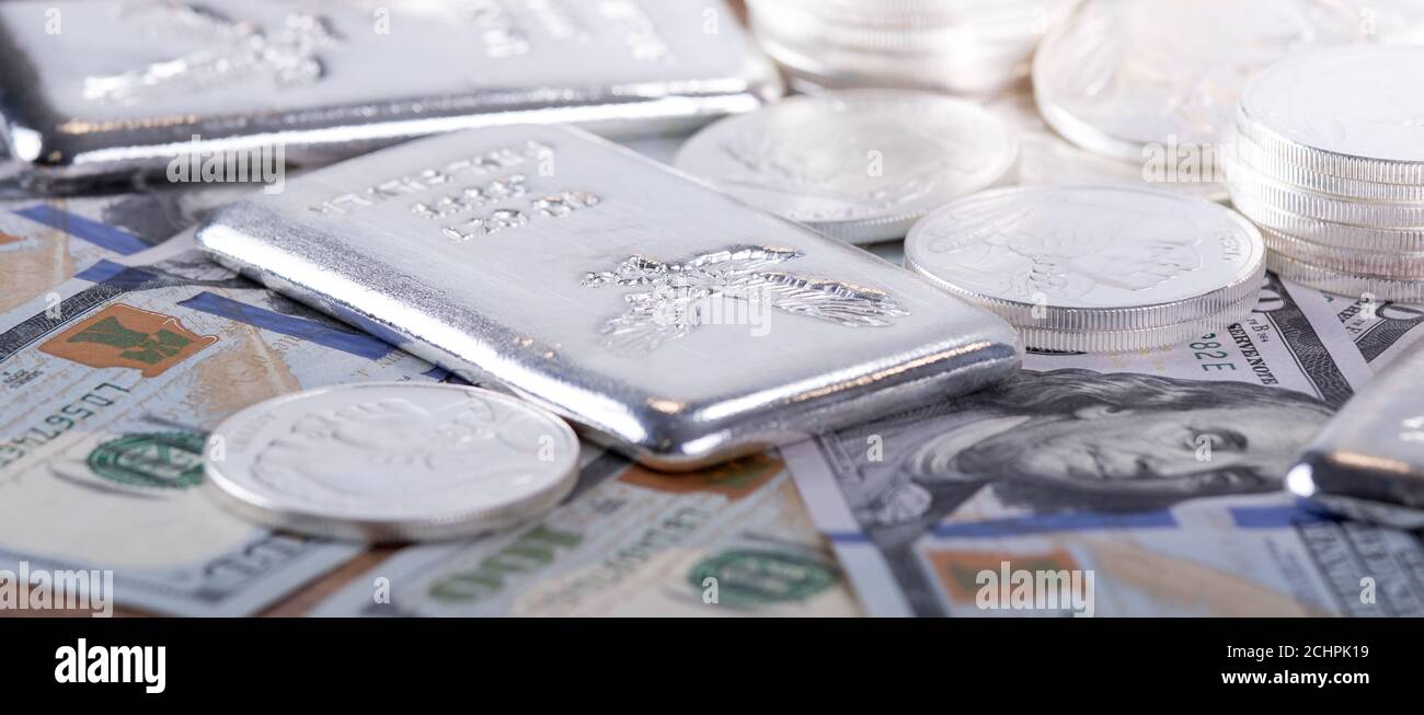 Closeup di barrette d'argento e monete d'argento e 100 dollari fatture Foto Stock