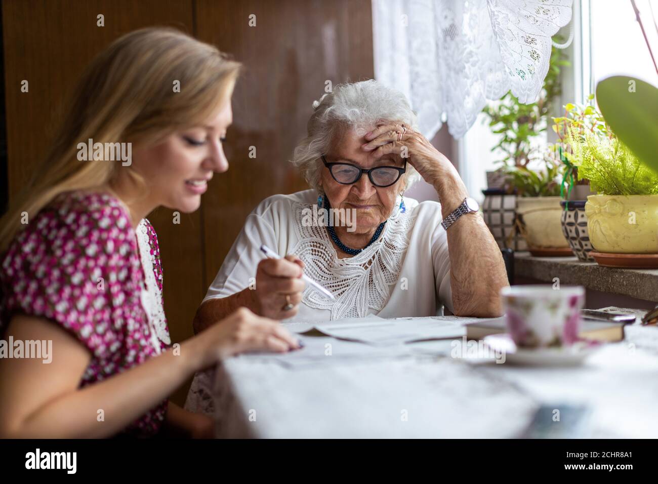 Giovane donna che aiuta la nonna anziana con i documenti Foto Stock