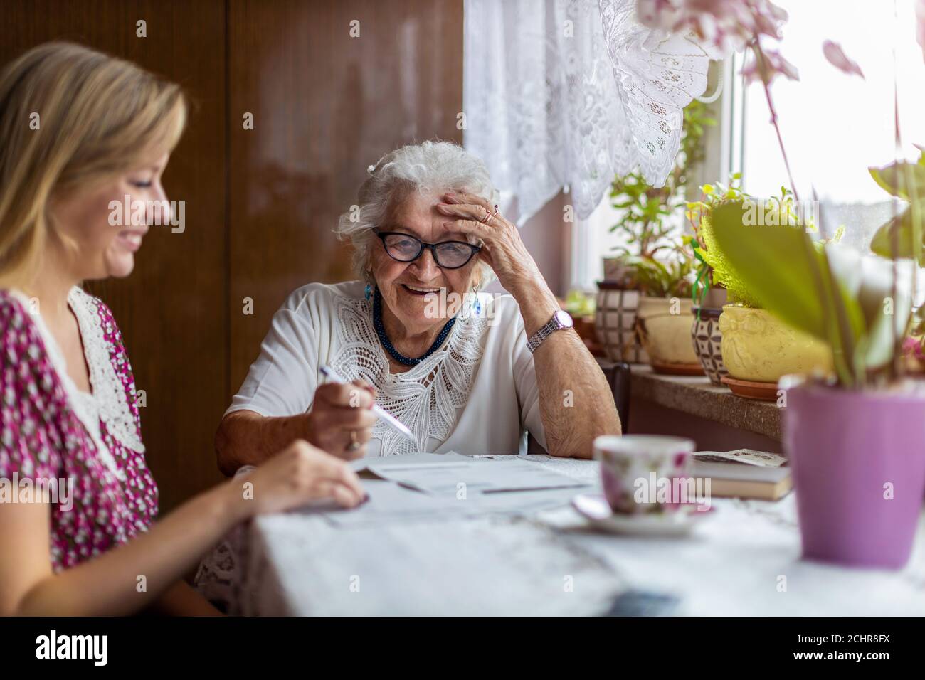 Giovane donna che aiuta la nonna anziana con i documenti Foto Stock