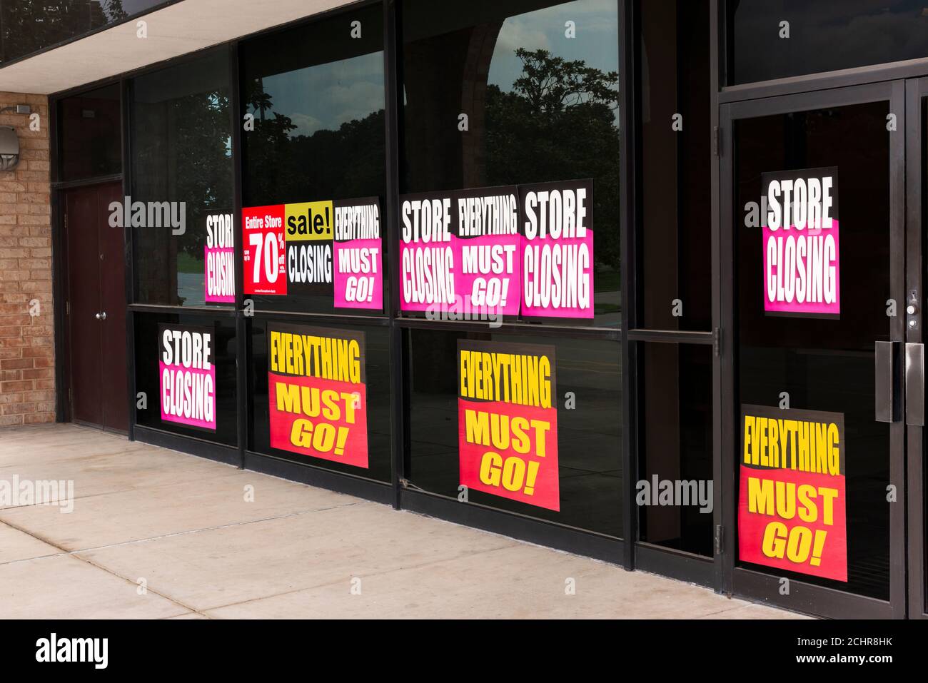 Inquadratura orizzontale angolata delle finestre di un negozio intonacato con l'uscita di cartelli aziendali a causa della pandemia. Foto Stock