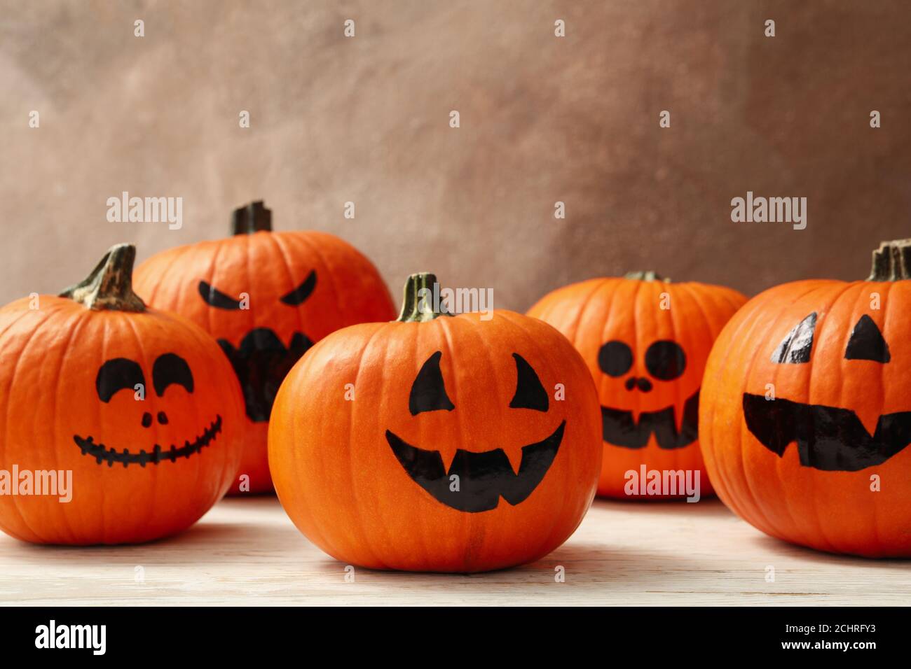 Sfondo marrone con divertenti zucche di Halloween, un accogliente concetto di festa autunnale per inviti Foto Stock