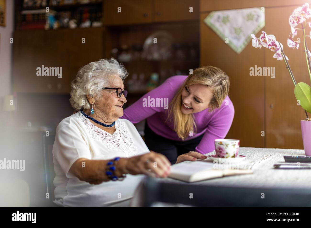 Giovane donna che passa il tempo con la nonna anziana a casa Foto Stock
