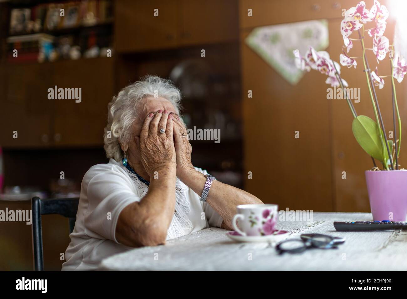 Donna anziana che tiene la testa nelle mani nella disperazione Foto Stock