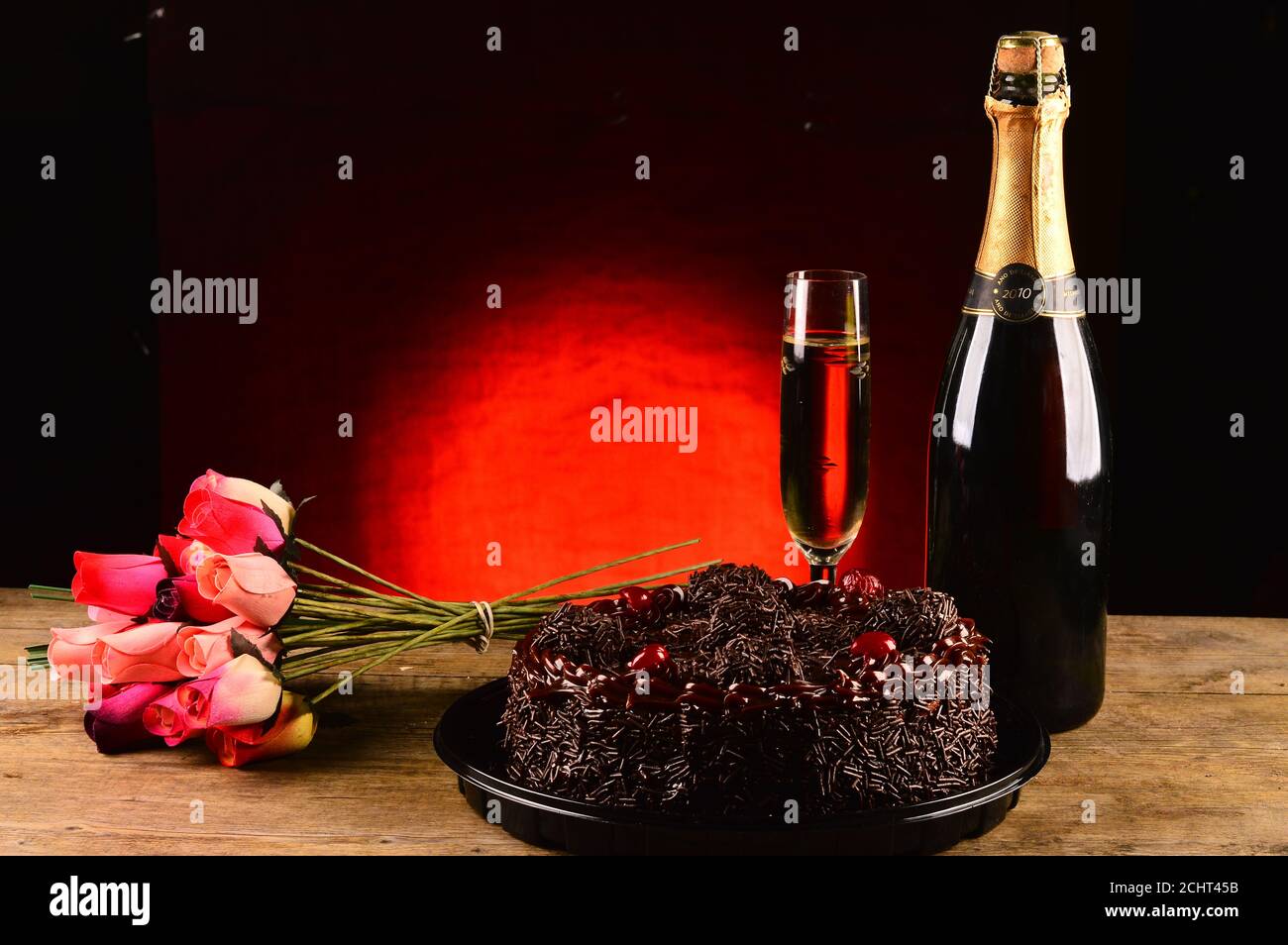 Torta al cioccolato, secchio di fiori e bottiglia di champagne in una foto in studio Foto Stock