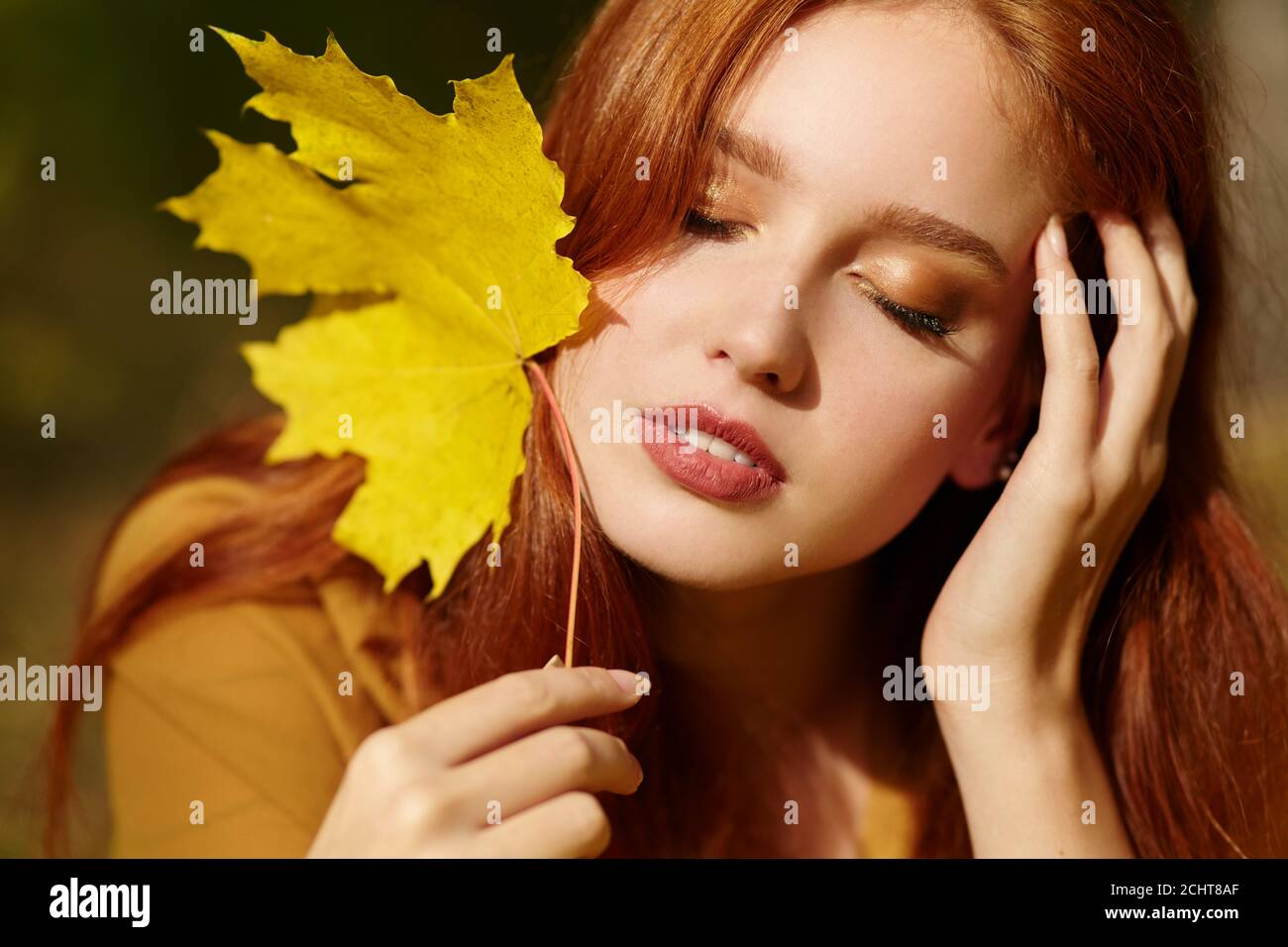 Donna di colore giallo con foglie di acero in autunno Foto Stock