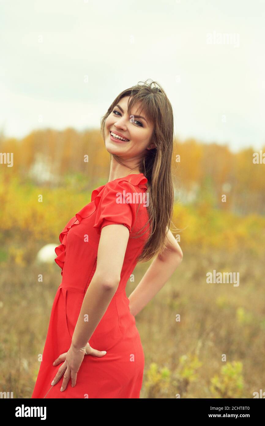 ritratto autunnale di una bella bruna donna di mezza età dentro un abito rosso Foto Stock