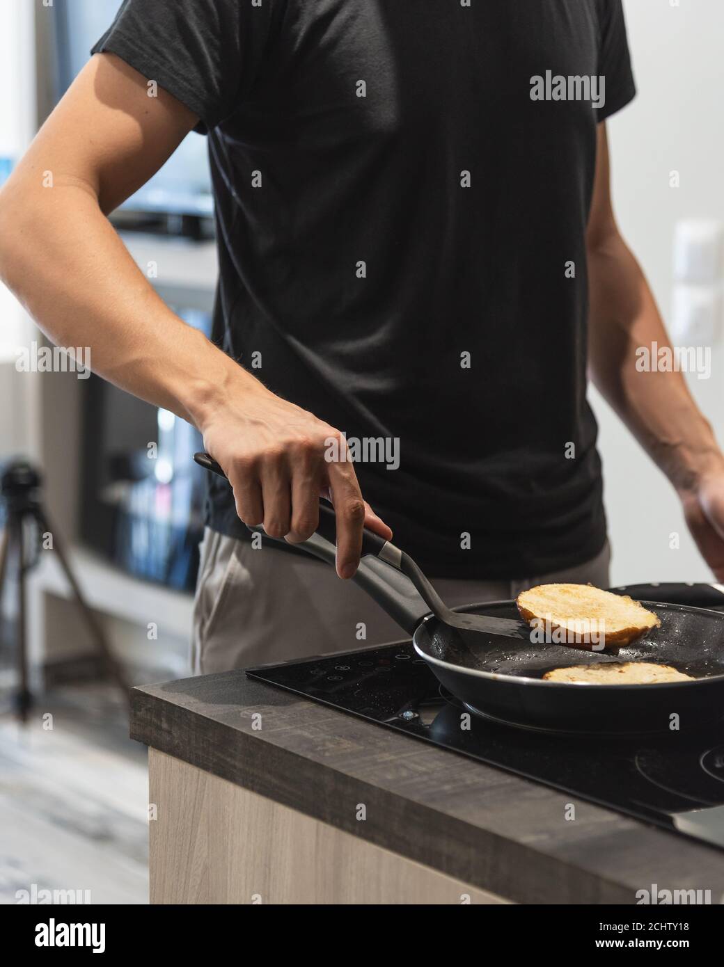 Giovane uomo che tostano panini da hamburger in padella a casa Foto Stock