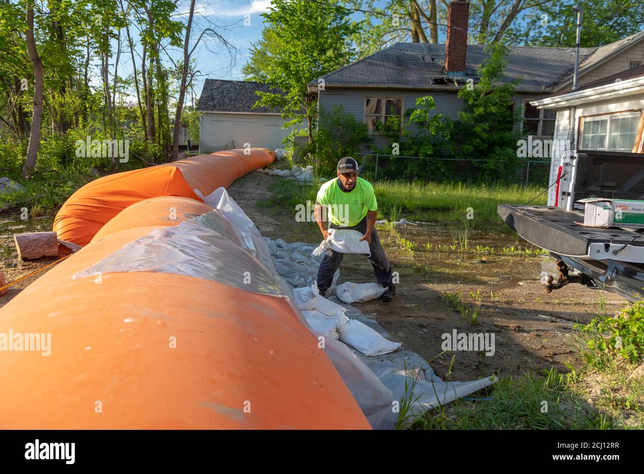 Detroit, Michigan - UN lavoratore posiziona i sacchi di sabbia per costeggiare una "diga della tigre" arancione vicino a un canale che collega al fiume Detroit e ai grandi Laghi. Il p Foto Stock