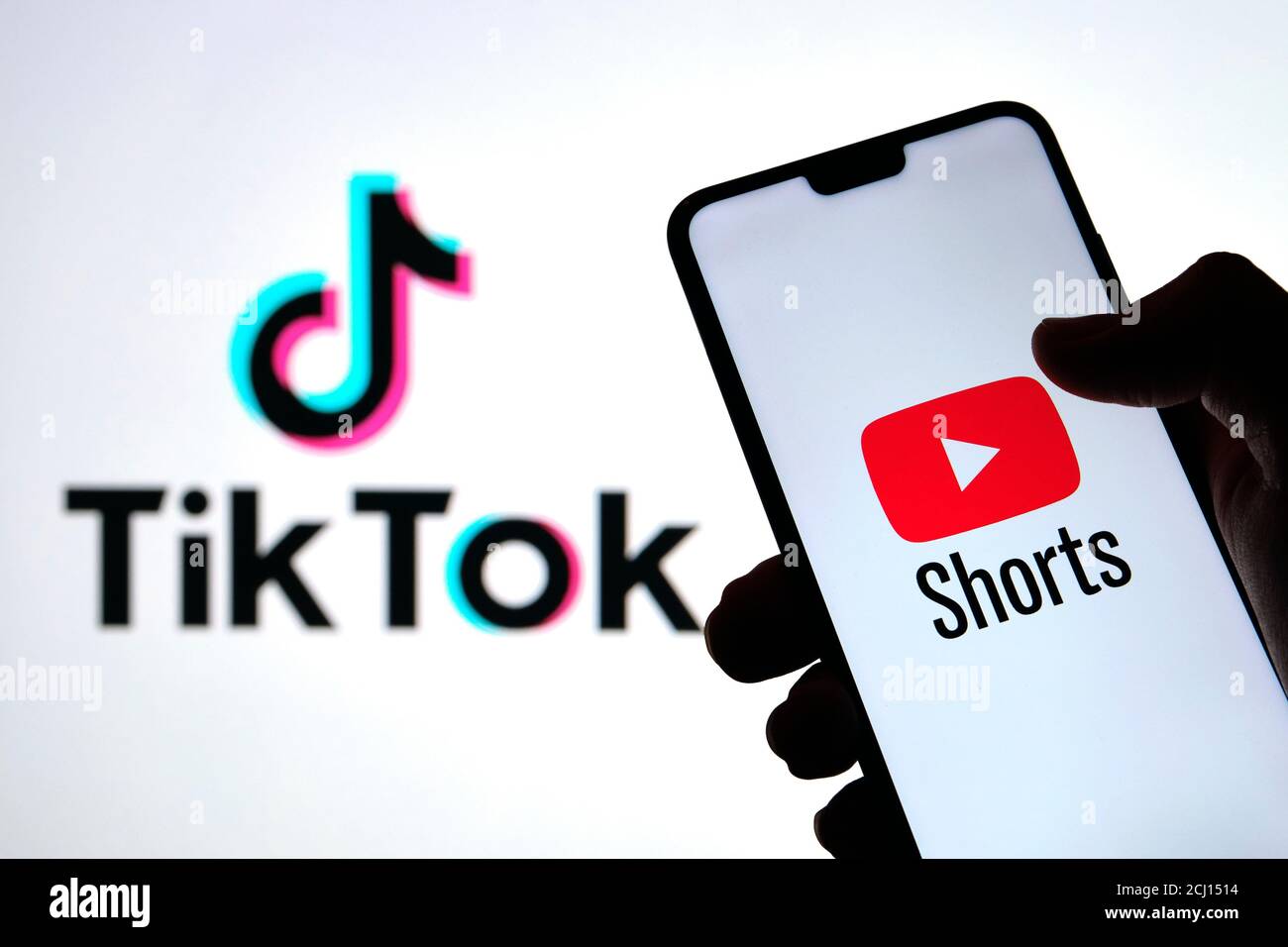 YouTube Shorts il logo dell'app visto sulla silhouette dello smartphone in una mano e il logo TikTok sullo sfondo sfocato. Foto vera, non un montaggio. Foto Stock