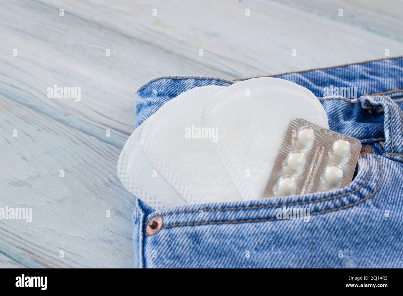 Compresse in una bugia shinped accanto alle pastiglie quotidiane delle donne in una tasca in denim Foto Stock