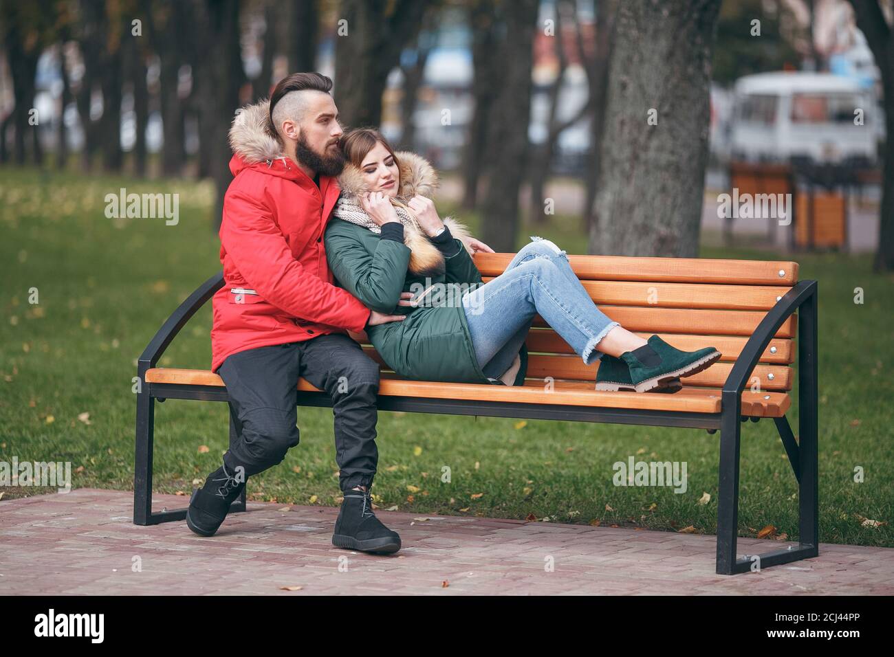 Un ragazzo e una ragazza si riposano su una panchina in un parco autunnale Foto Stock