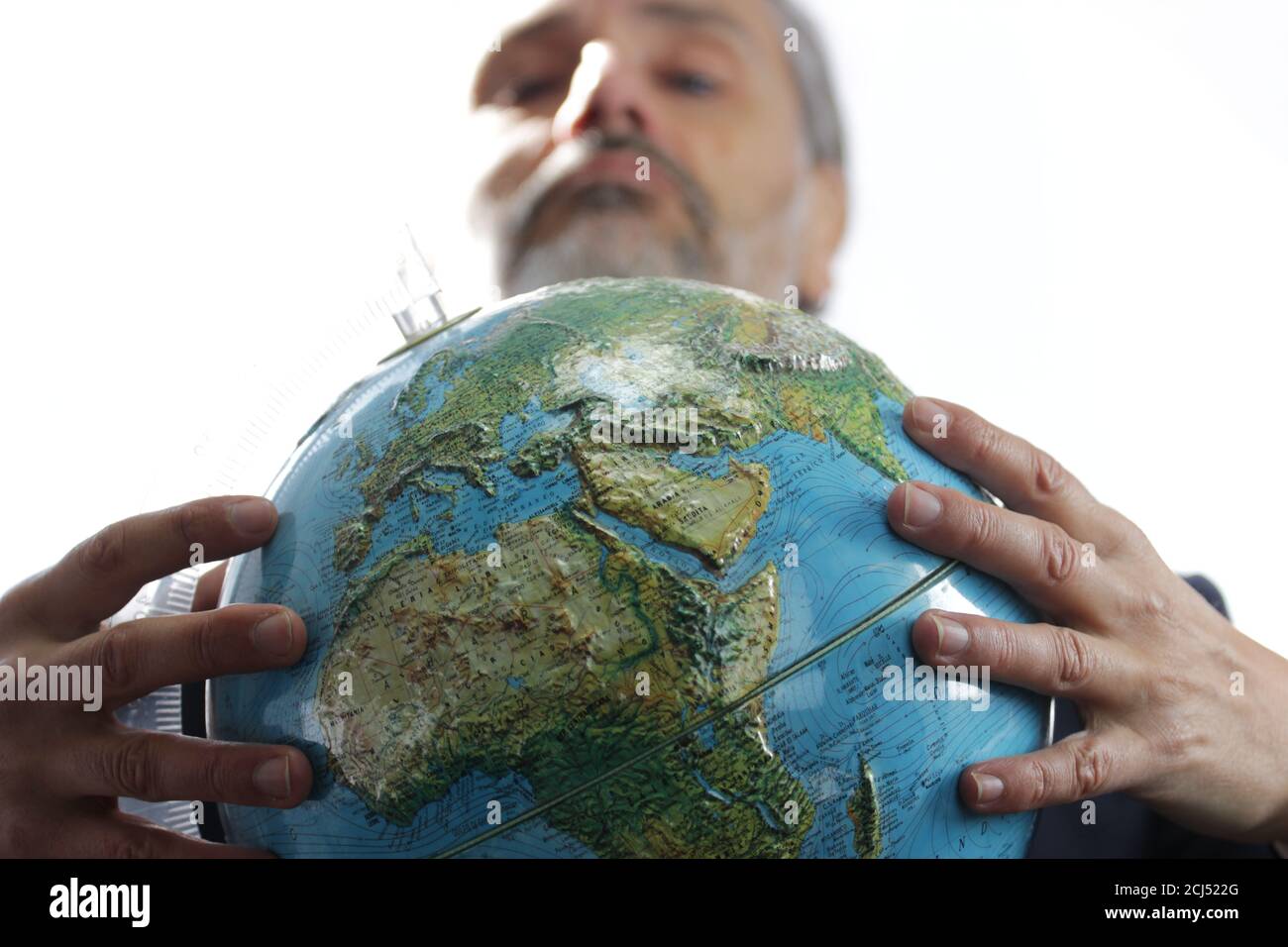 Colpo di primo piano di un maschio anziano con una barba che tiene un concetto globo-dio Foto Stock