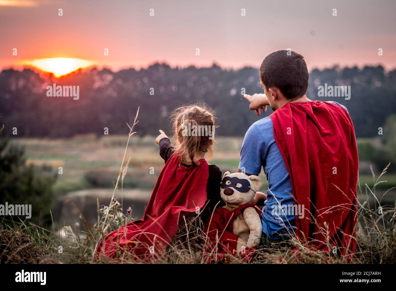 Bambina con il papà vestiti in super eroi, felice famiglia amorevole, padre e figlia giocare all'aperto, i valori della famiglia Foto Stock