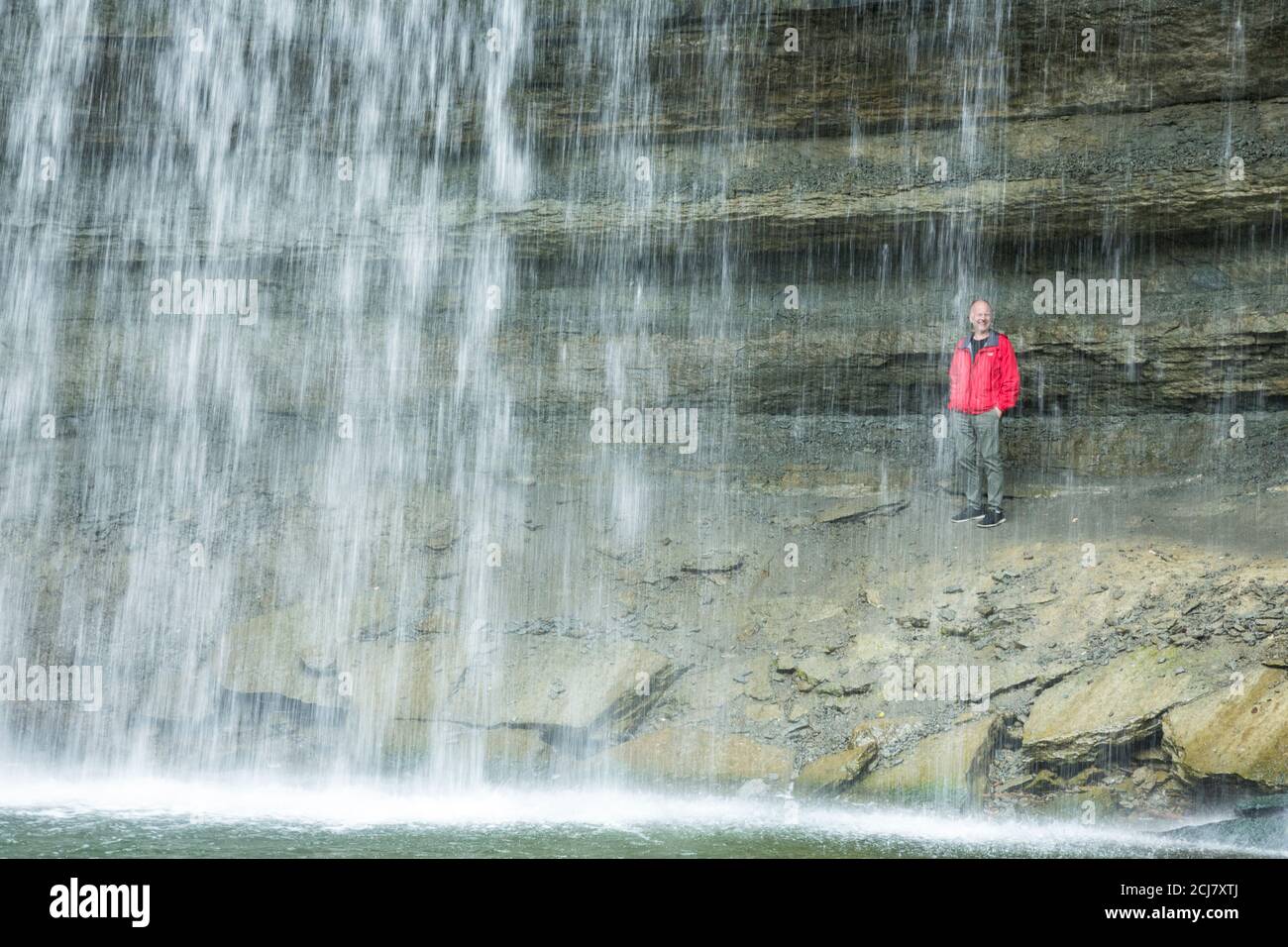 Uomo in giacca rossa dietro le cascate, Bridal Veil Falls, Manitoulin Island, Ontario, Canada Foto Stock