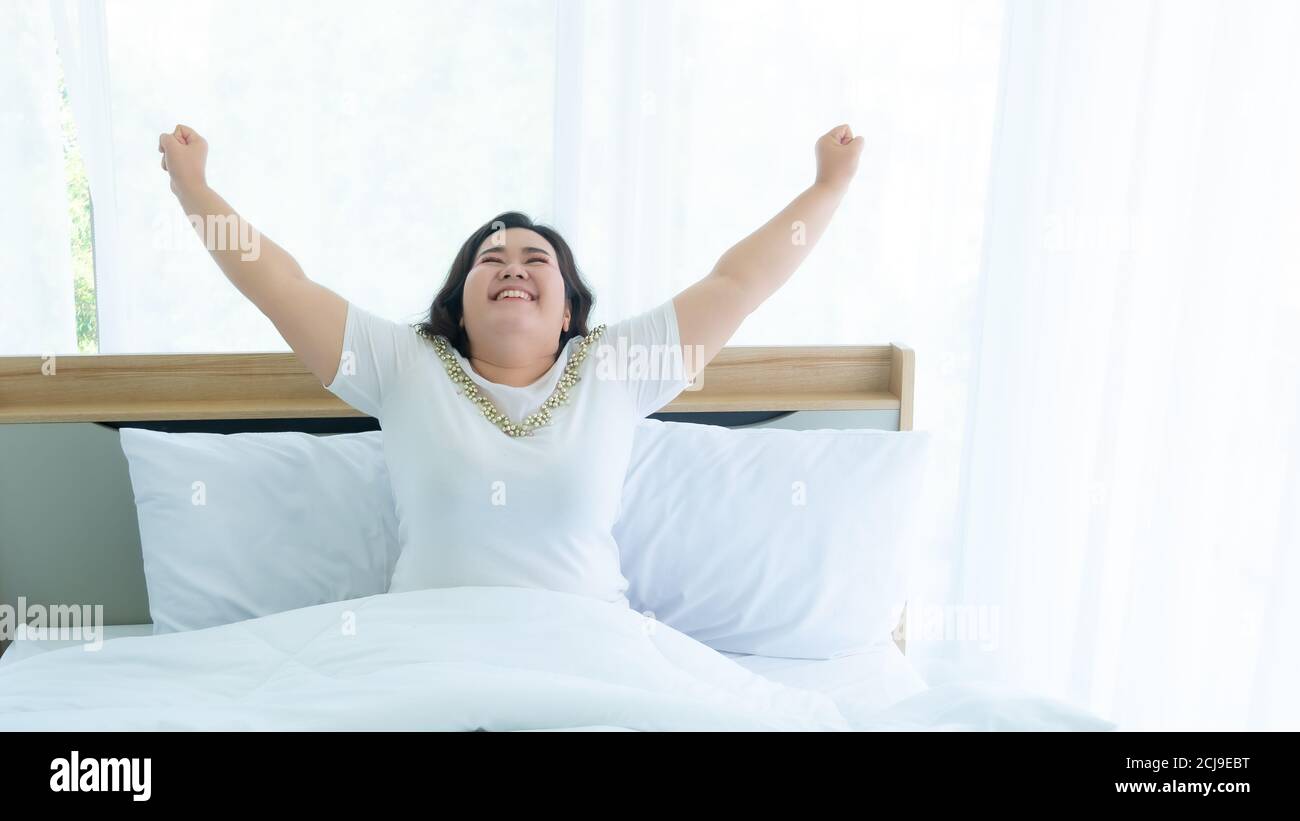 Le donne più la sveglia di dimensione e la felicità sul letto camera Foto Stock