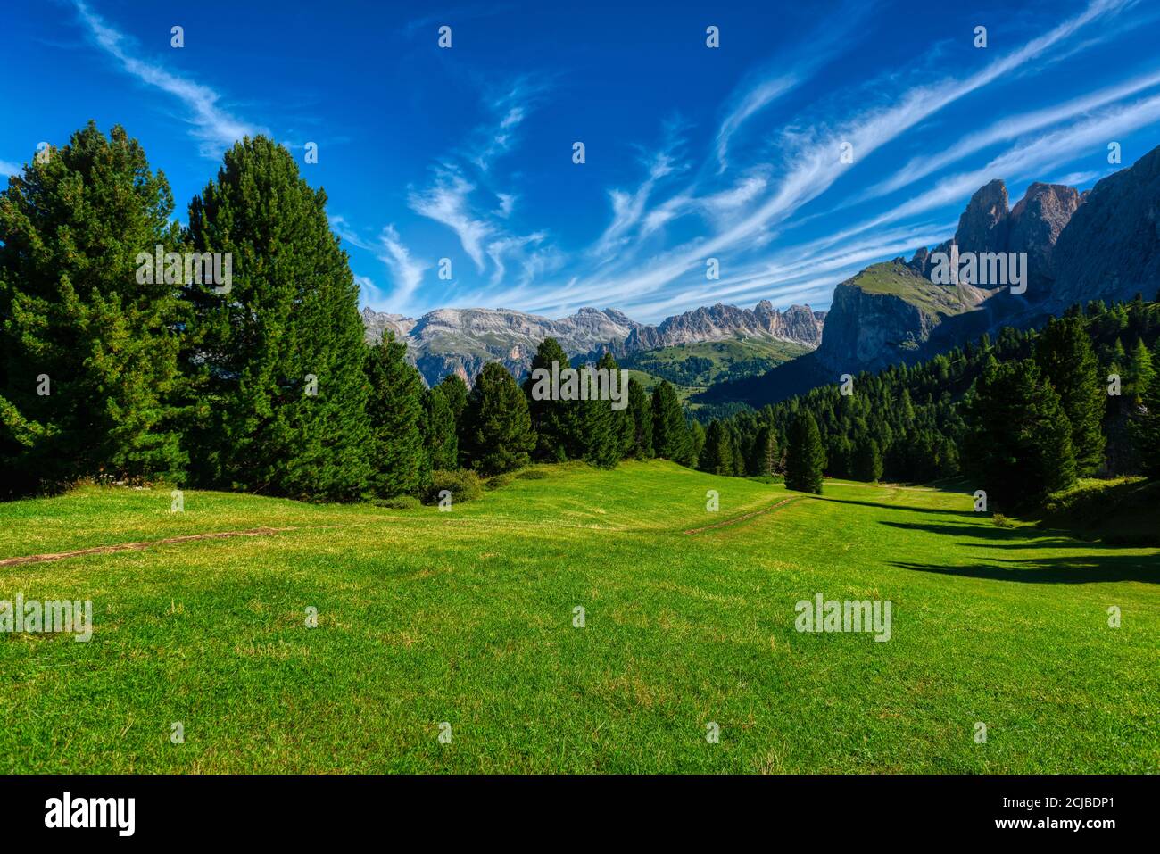 Paesaggio di prati verdi e montagne della Val Gardena in una mattinata estiva con sceniche nuvole nel cielo, Dolomiti Foto Stock