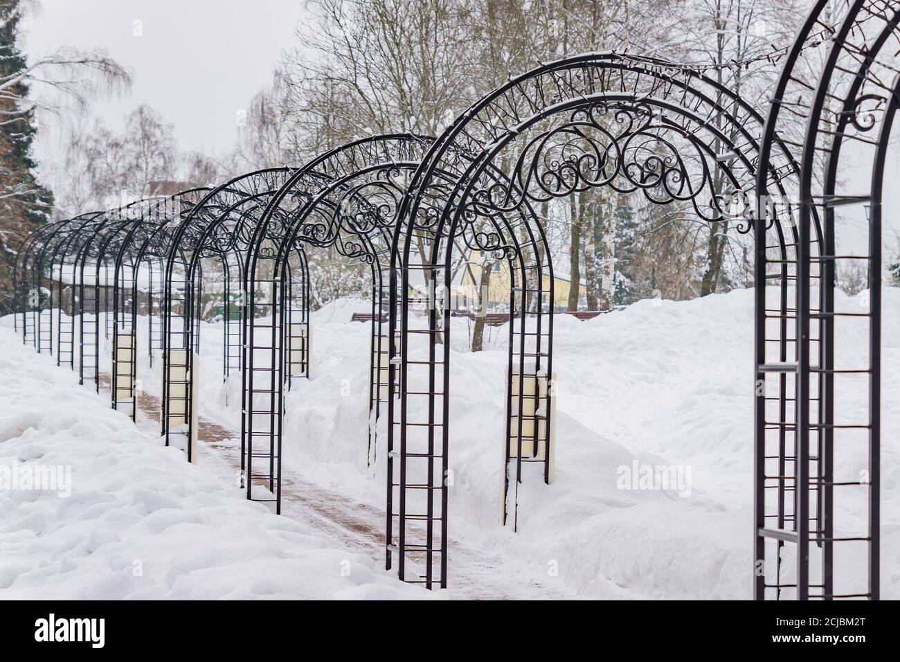 tunnel con archi in metallo forgiato nel parco invernale. Foto Stock