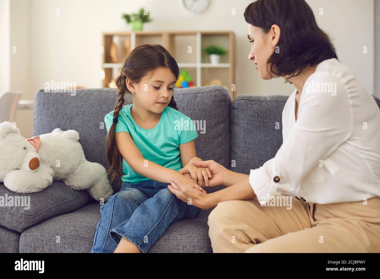 Madre seduta con la figlia, le tiene le mani, le parla e le insegna qualcosa Foto Stock