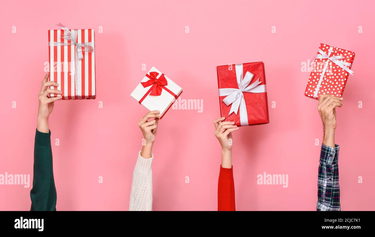 Mani che tengono e sollevano le scatole del regalo in sfondo rosa isolato Per Christmast e concetti di nuovo anno Foto Stock
