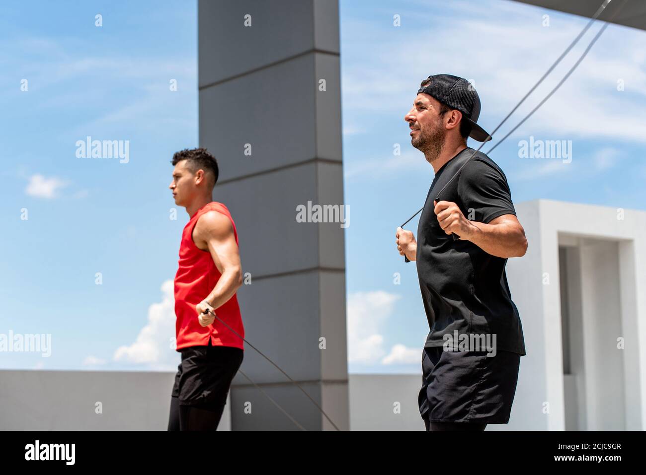 Due bei sportivi caucasici che fanno la mattina all'aperto saltando esercizio di corda sul tetto dell'edificio Foto Stock