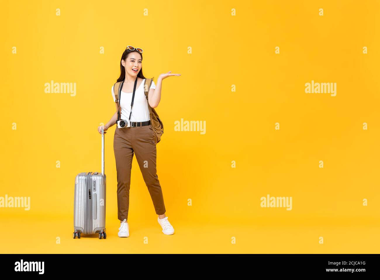 Ritratto a lunghezza intera di sorridente carino giovane turista asiatico apri la mano per copiare lo spazio isolato su sfondo giallo dello studio Foto Stock