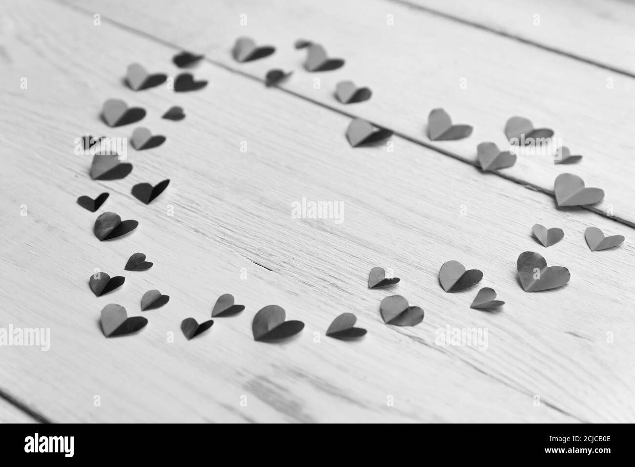 Cuore grande fatto di carta tagliata piccoli cuori su legno backround. Decorazione Handmaede per San Valentino. Bianco e nero Foto Stock