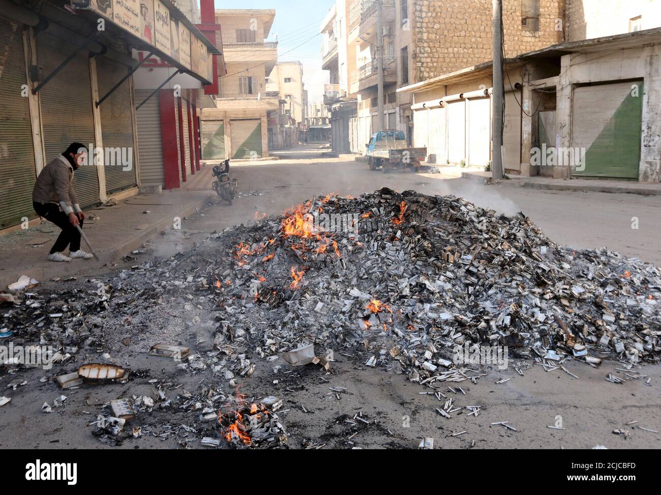 Un uomo si trova vicino alle sigarette confiscate, incendiate dai membri del fronte Nusra di al Qaeda nella città di Idlib il 31 marzo 2015. Gruppi islamici, tra cui il fronte Nusra di al Qaeda, hanno sequestrato la città di Idlib per la prima volta nella guerra civile in Siria, combattenti e un gruppo di monitoraggio ha detto sabato. Foto scattata il 31 marzo 2015. REUTERS/Ammar Abdullah Foto Stock