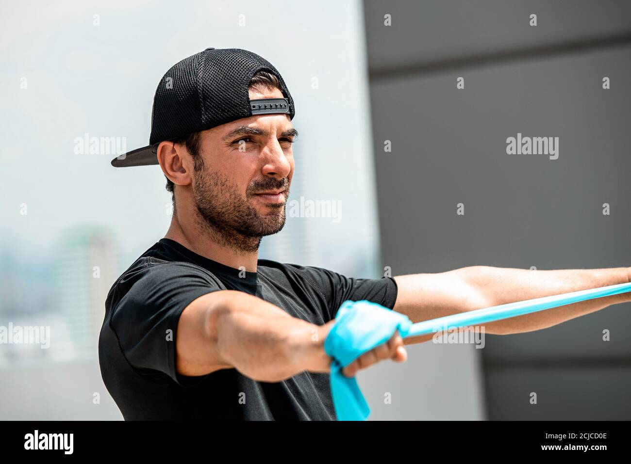 Bell'sportivo caucasico che fa esercizio di trazione con la banda di resistenza dentro tetto all'aperto Foto Stock