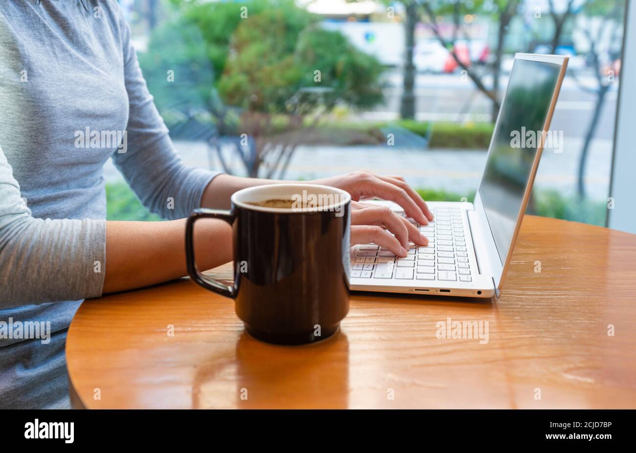 Utilizzando un computer portatile e gustando un caffè in un bar Foto Stock