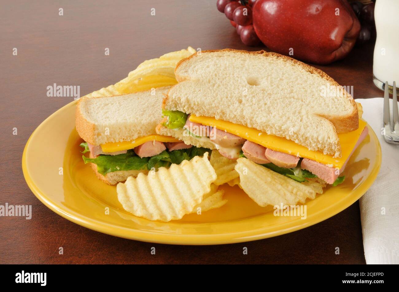 Un sandwich viennese con salsiccia e formaggio con latte e frutta Foto Stock