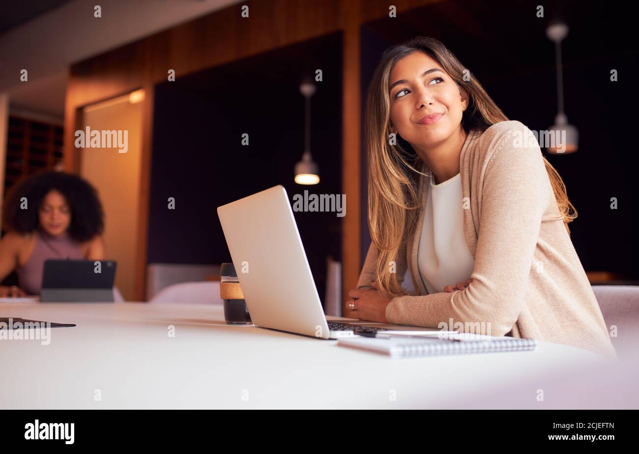 Donna d'affari con il laptop alla riunione socialmente distanziata in ufficio durante Pandemic di salute Foto Stock