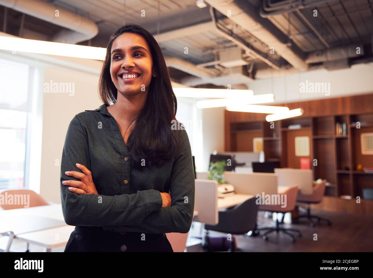 Ritratto di sorridente Businesswoman in piedi in un moderno ufficio a pianta aperta Foto Stock