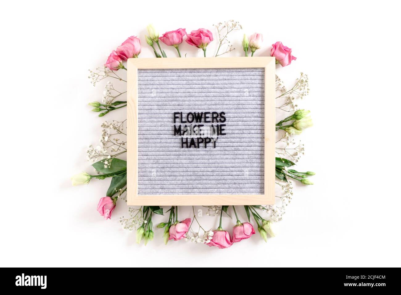 Citazione Fiori mi rendono felice. Letter .Board con corona fatta di fiori su sfondo bianco Foto Stock