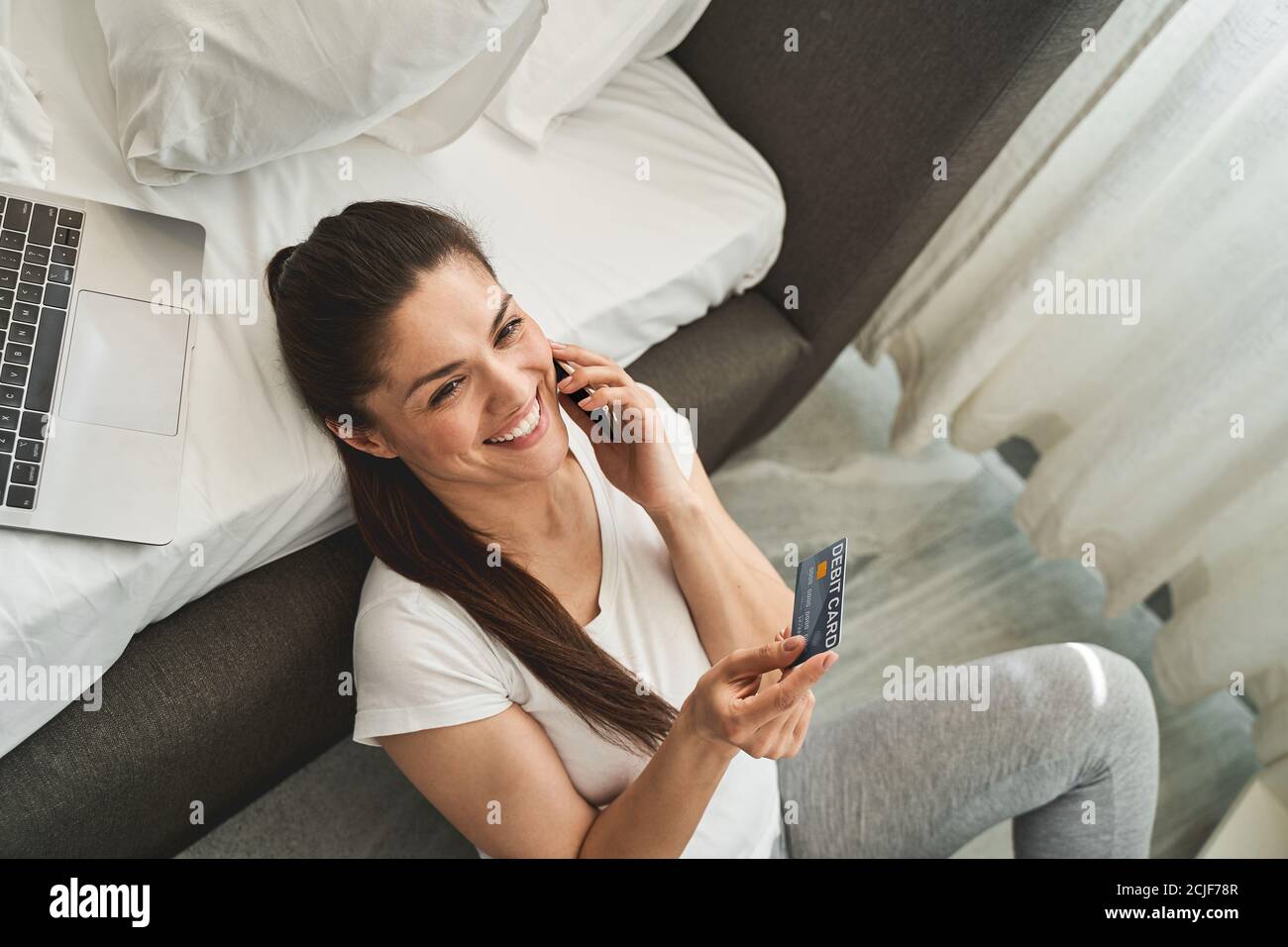 Donna allegra che tiene una carta di debito in una mano Foto Stock