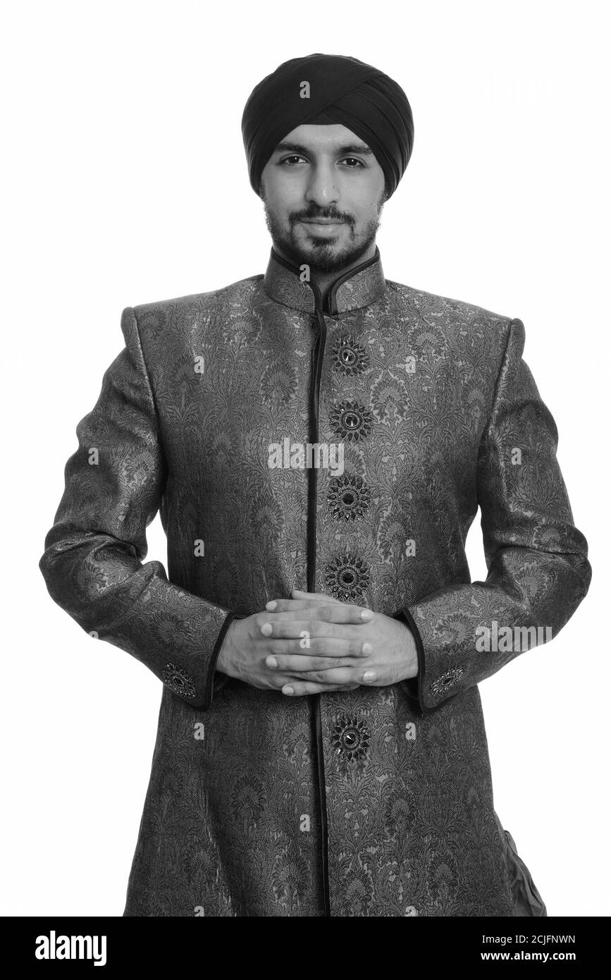 Giovane bell'uomo indiano Sikh intreccia le dita insieme indossando tradizionale vestiti Foto Stock
