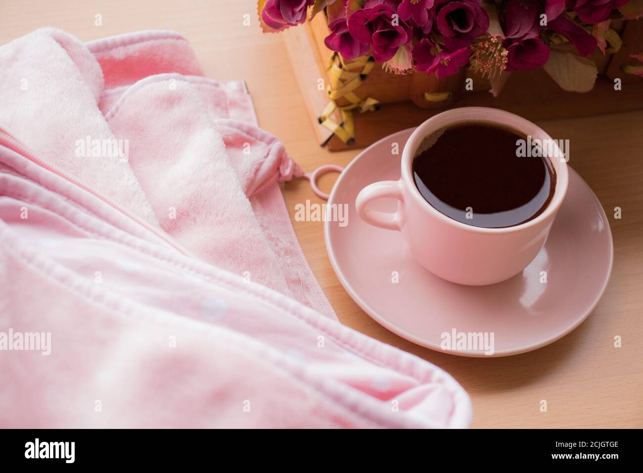 tazza rosa di caffè nero e il fiore rosa, su sfondo di tessitura di legno. Concetto di piatto. Vista dall'alto. Caffè del mattino. Giornata internazionale del caffè. Foto Stock