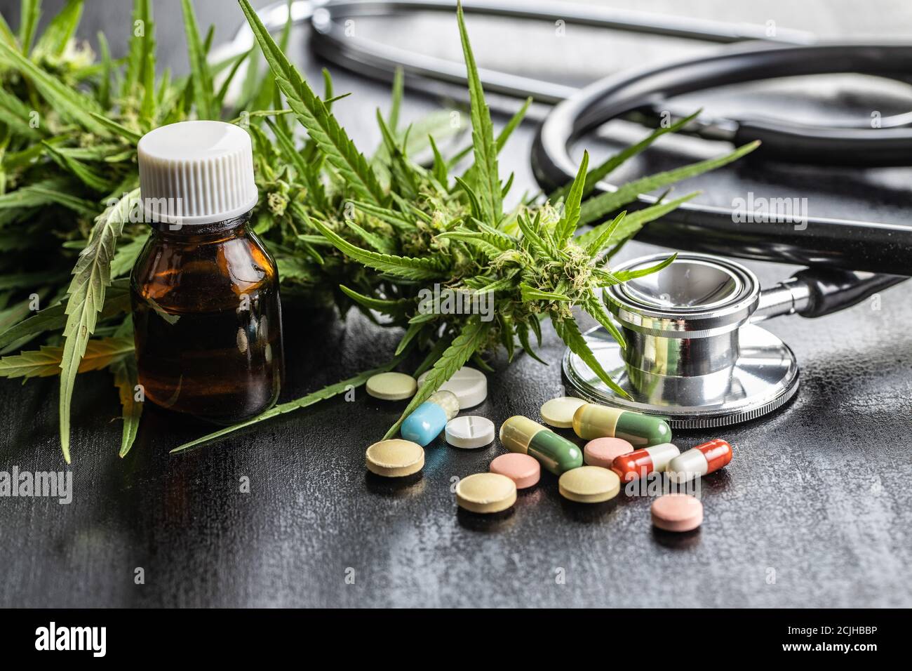 Boccioli di marijuana fiori di cannabis, stetoscopio, pillole e olio su tavola nera. Foto Stock