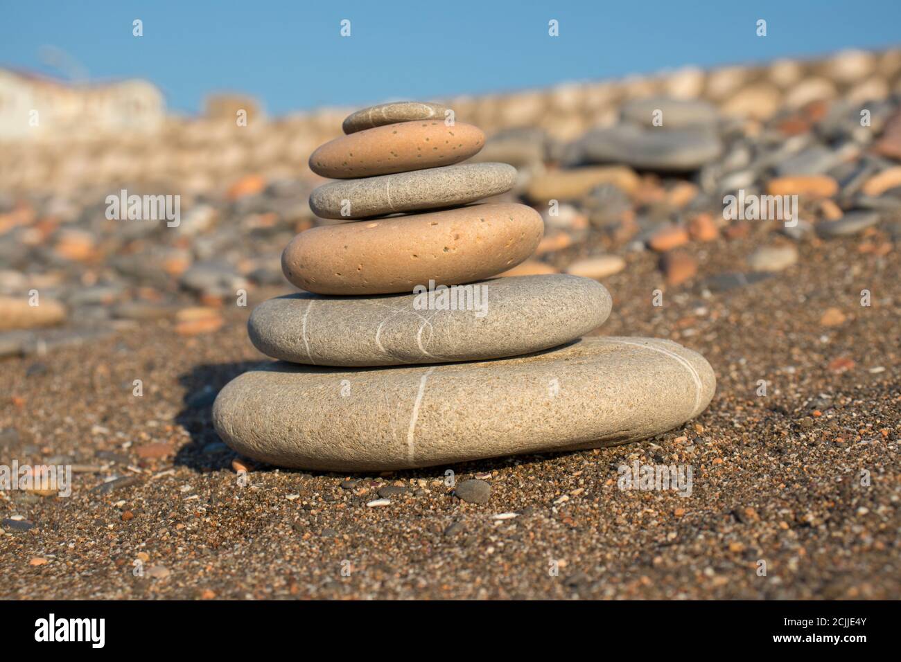 torre di pietra fatta a mano su una spiaggia di ghiaia e sabbia. Piramide di ciottoli grigi. Zen scultura. Carta da parati. Concetto di vacanza estiva. Foto Stock