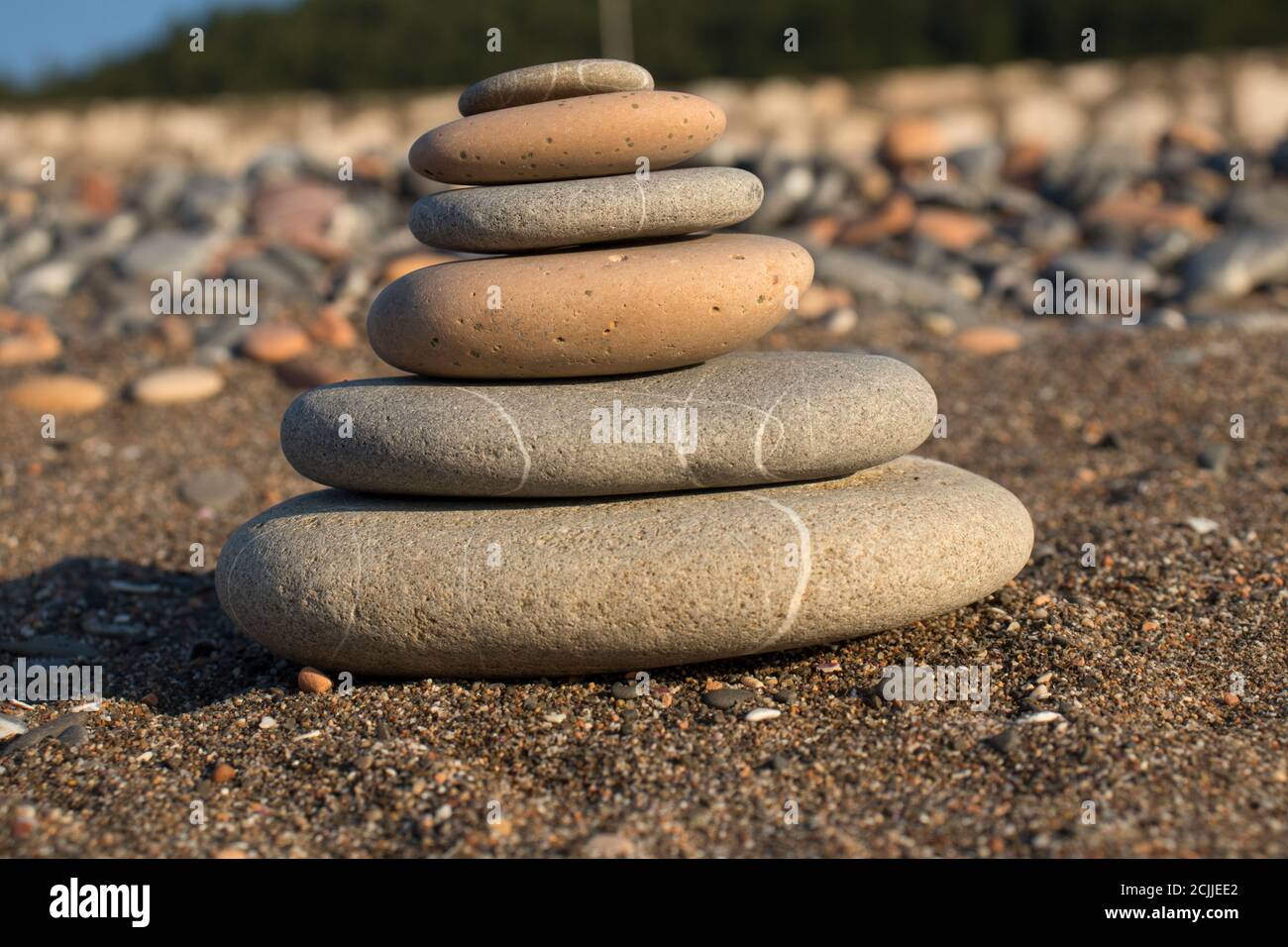 torre di pietra fatta a mano su una spiaggia di ghiaia e sabbia. Piramide di ciottoli grigi. Zen scultura. Carta da parati. Concetto di vacanza estiva. Foto Stock