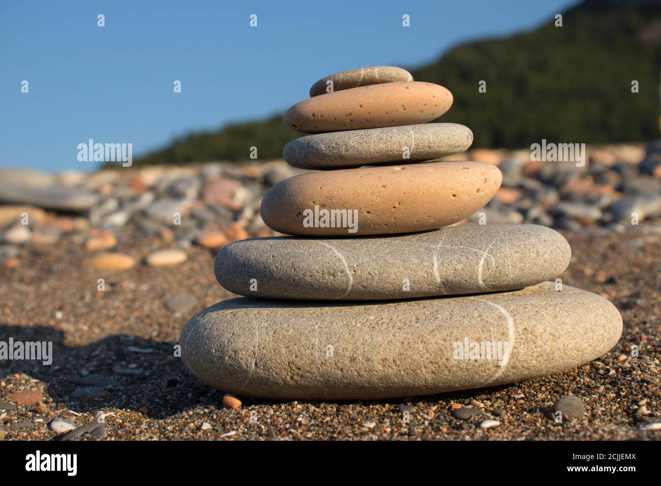 torre di pietra fatta a mano su una spiaggia di ghiaia e sabbia. Piramide di ciottoli grigi. Zen scultura. Carta da parati. Concetto di vacanza estiva. Foto Stock