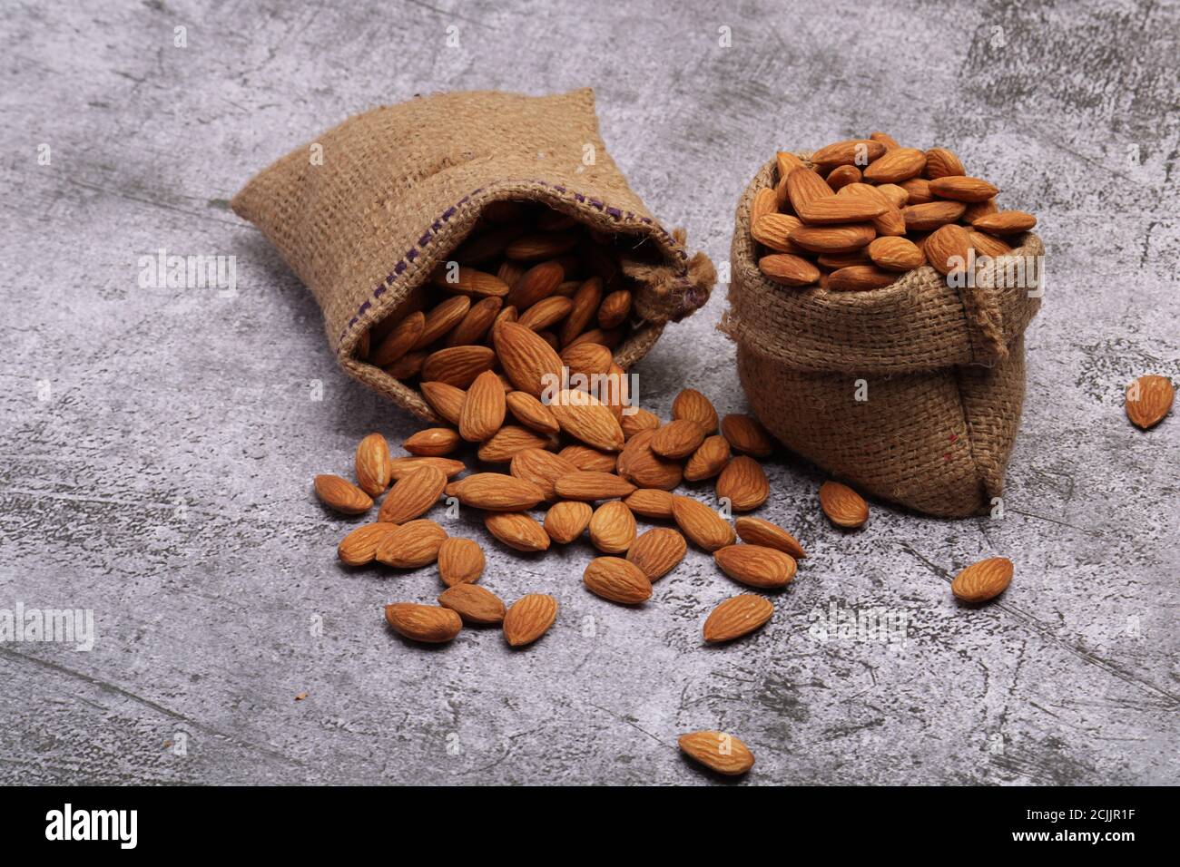 Mandorle in sacchetto isolate su sfondo grigio. Foto Stock